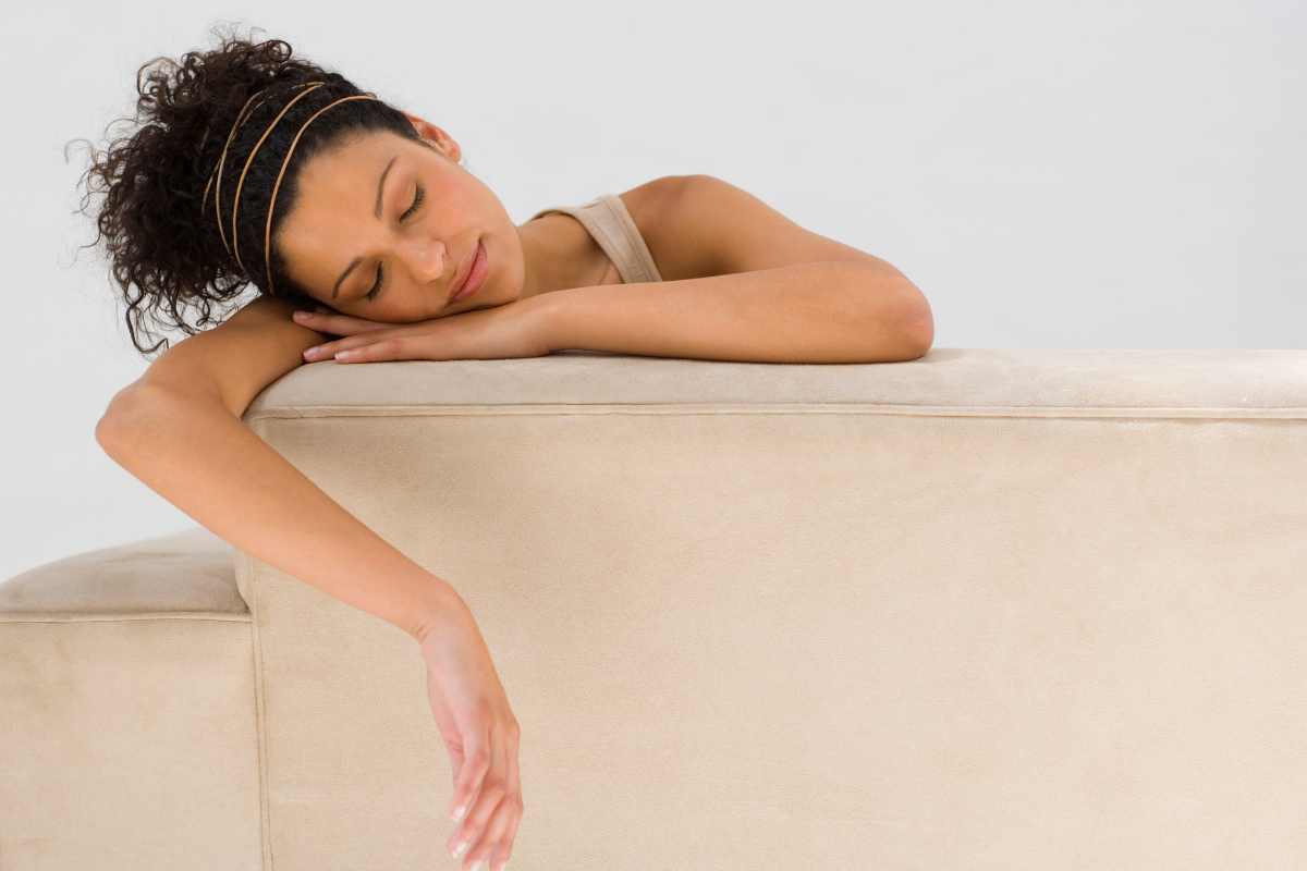 Personne dormant sur un canapé beige.