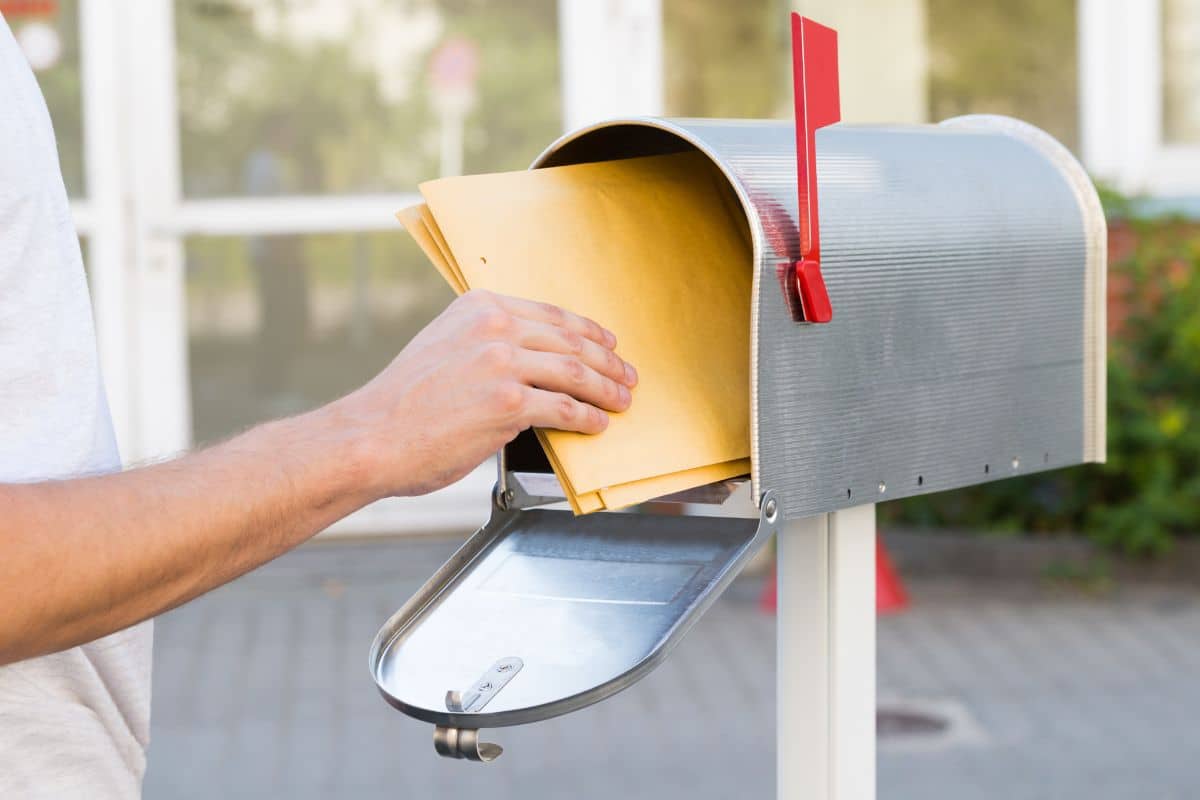 Main plaçant enveloppes dans une boîte aux lettres.