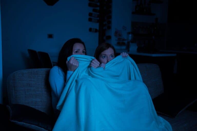 Deux personnes se cachent sous une couverture effrayées.