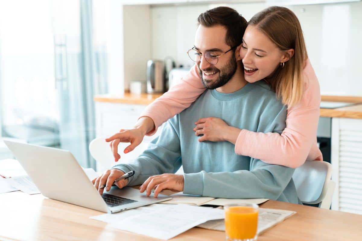 Couple souriant utilisant un ordinateur portable ensemble