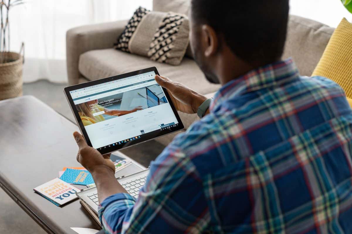 Homme utilisant une tablette dans un salon moderne.