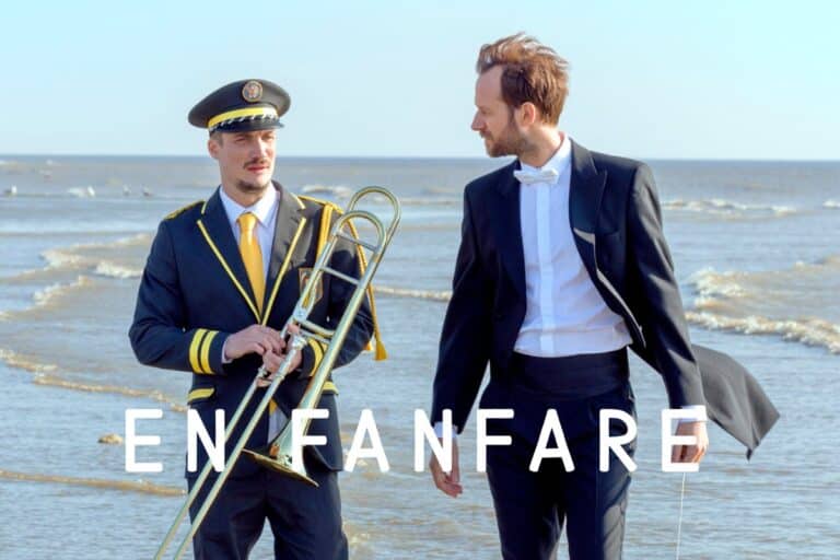 Deux hommes sur la plage en costumes élégants.