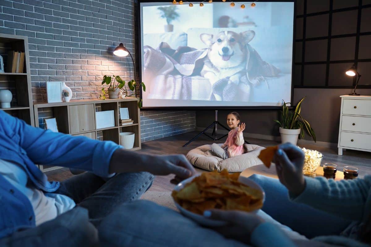 Enfant regardant un film avec des adultes et snacks.