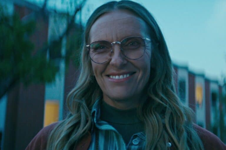 Personne souriante avec lunettes et cheveux longs.