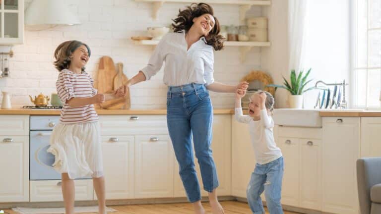 Famille dansant joyeusement dans la cuisine lumineuse.