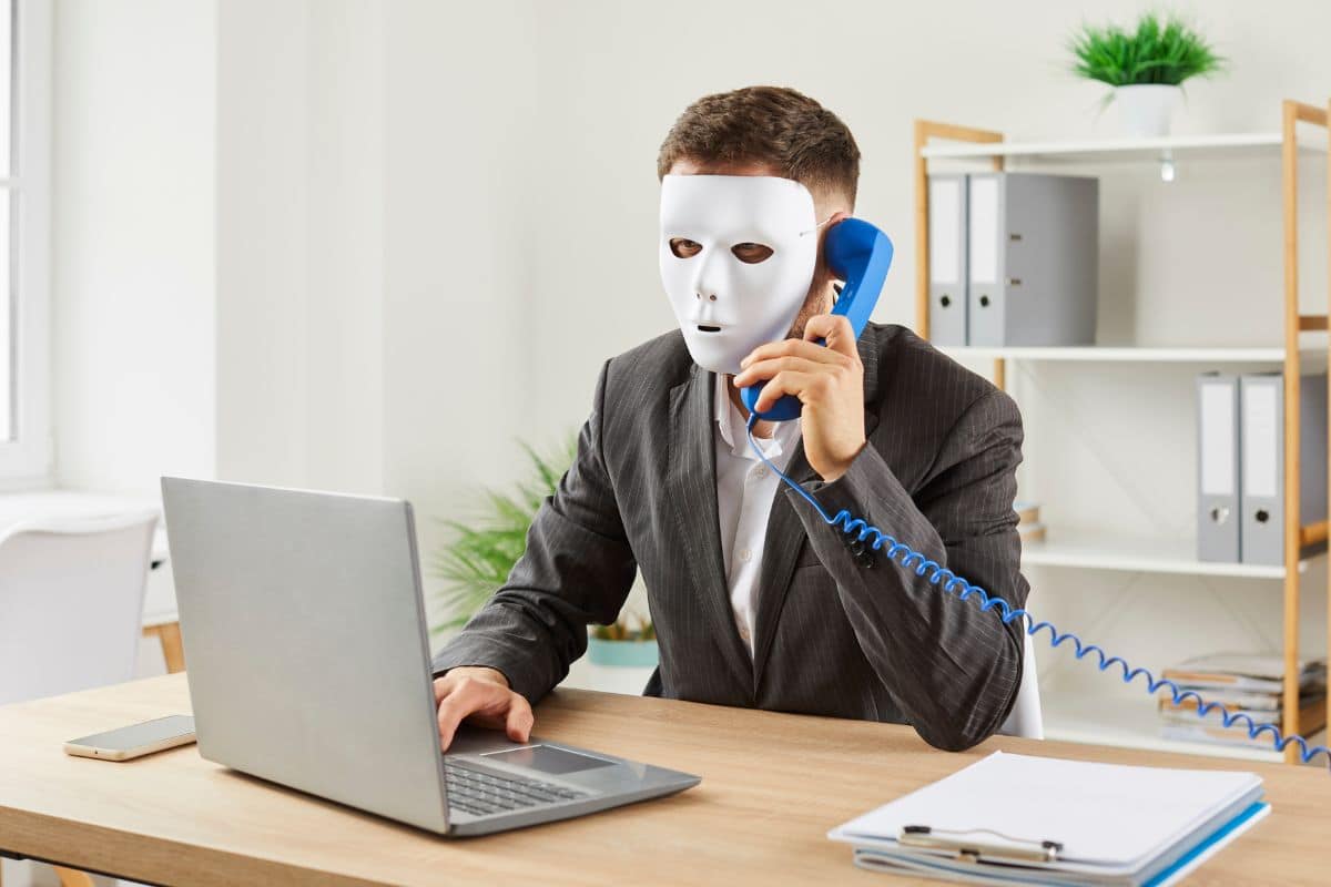 Homme masqué téléphone au bureau.