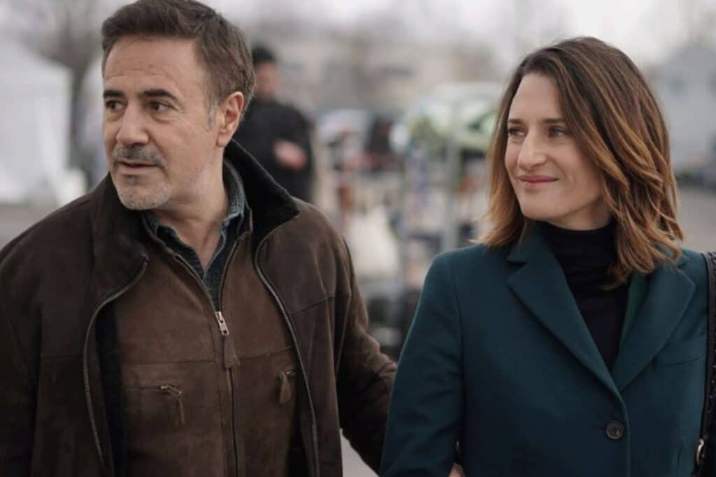 Homme et femme souriants, marchant ensemble dehors.