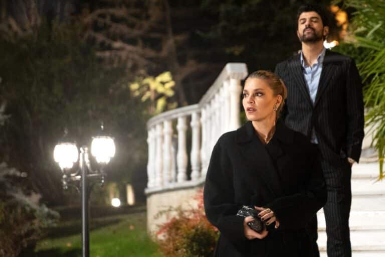 Deux personnes élégantes devant un escalier.