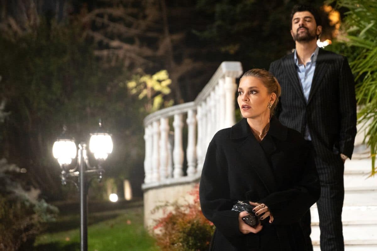 Deux personnes élégantes devant un escalier.