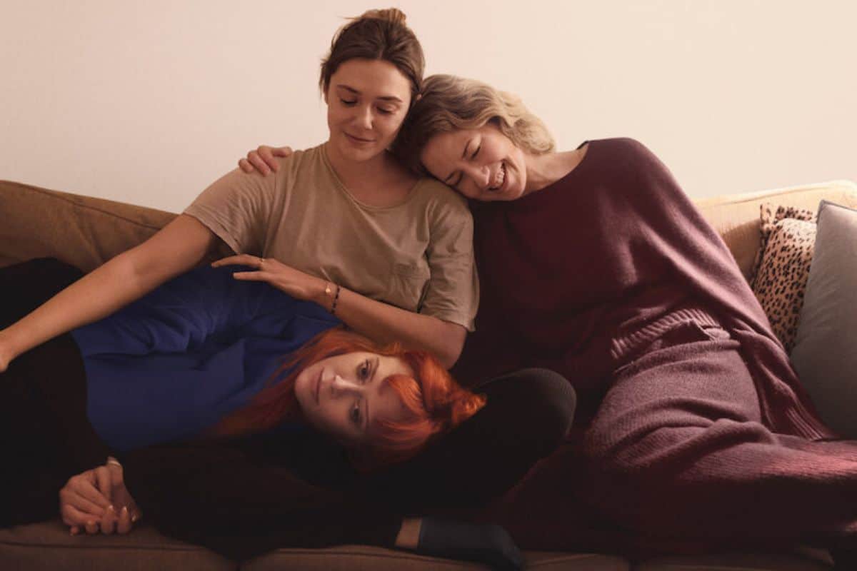 Trois femmes souriantes assises sur un canapé.