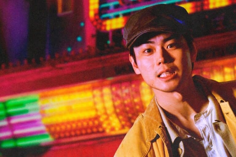 Personne portant casquette devant lumières colorées.