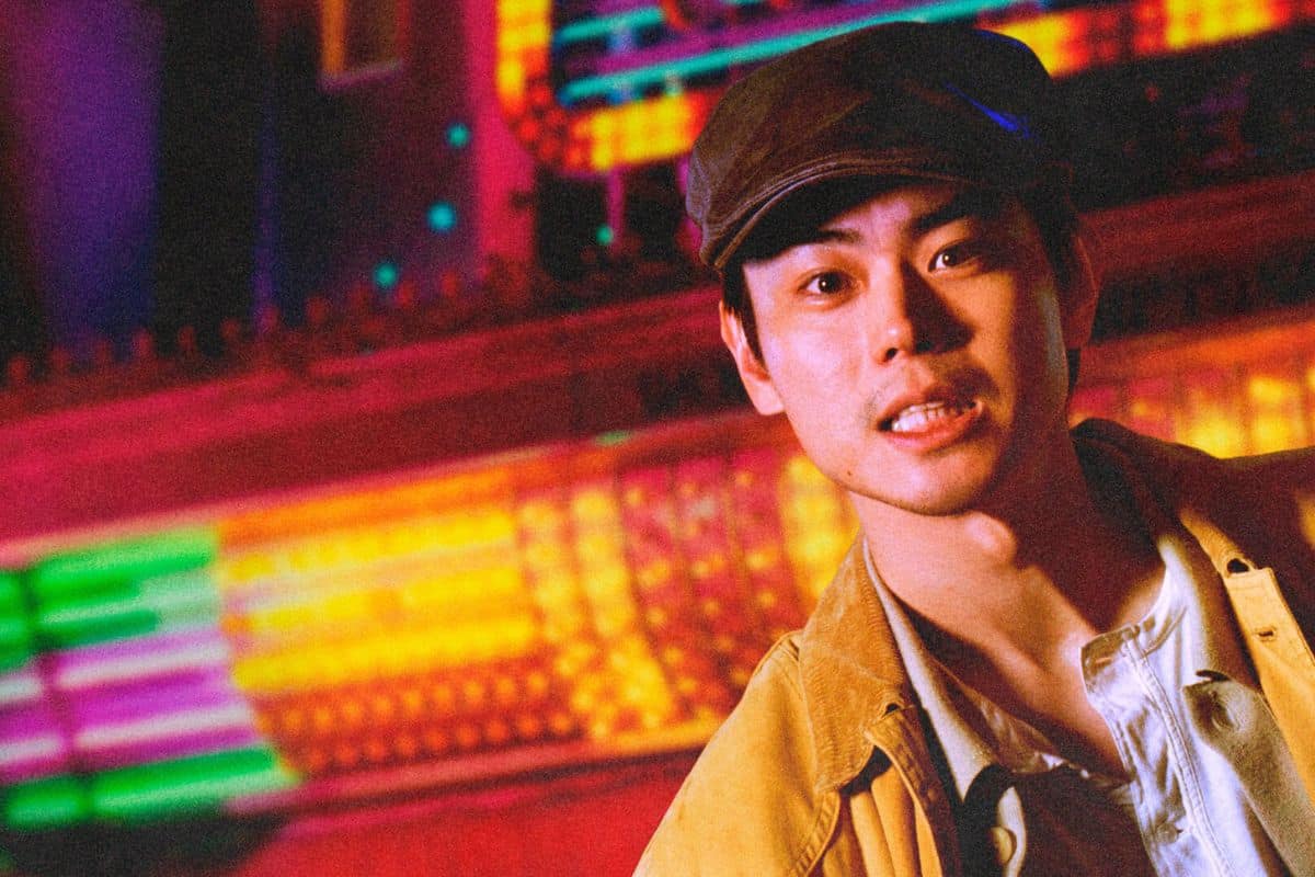 Personne portant casquette devant lumières colorées.