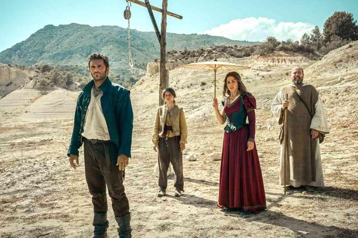 Groupe de personnes devant potence, paysage montagneux.