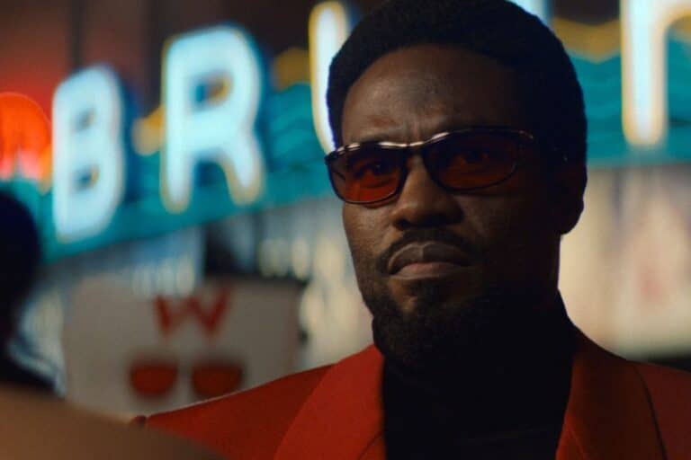 Homme portant des lunettes de soleil, fond lumineux.