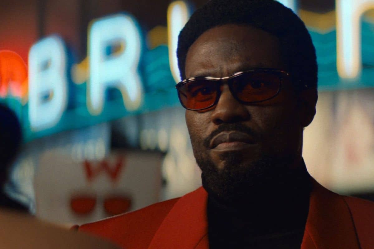 Homme portant des lunettes de soleil, fond lumineux.