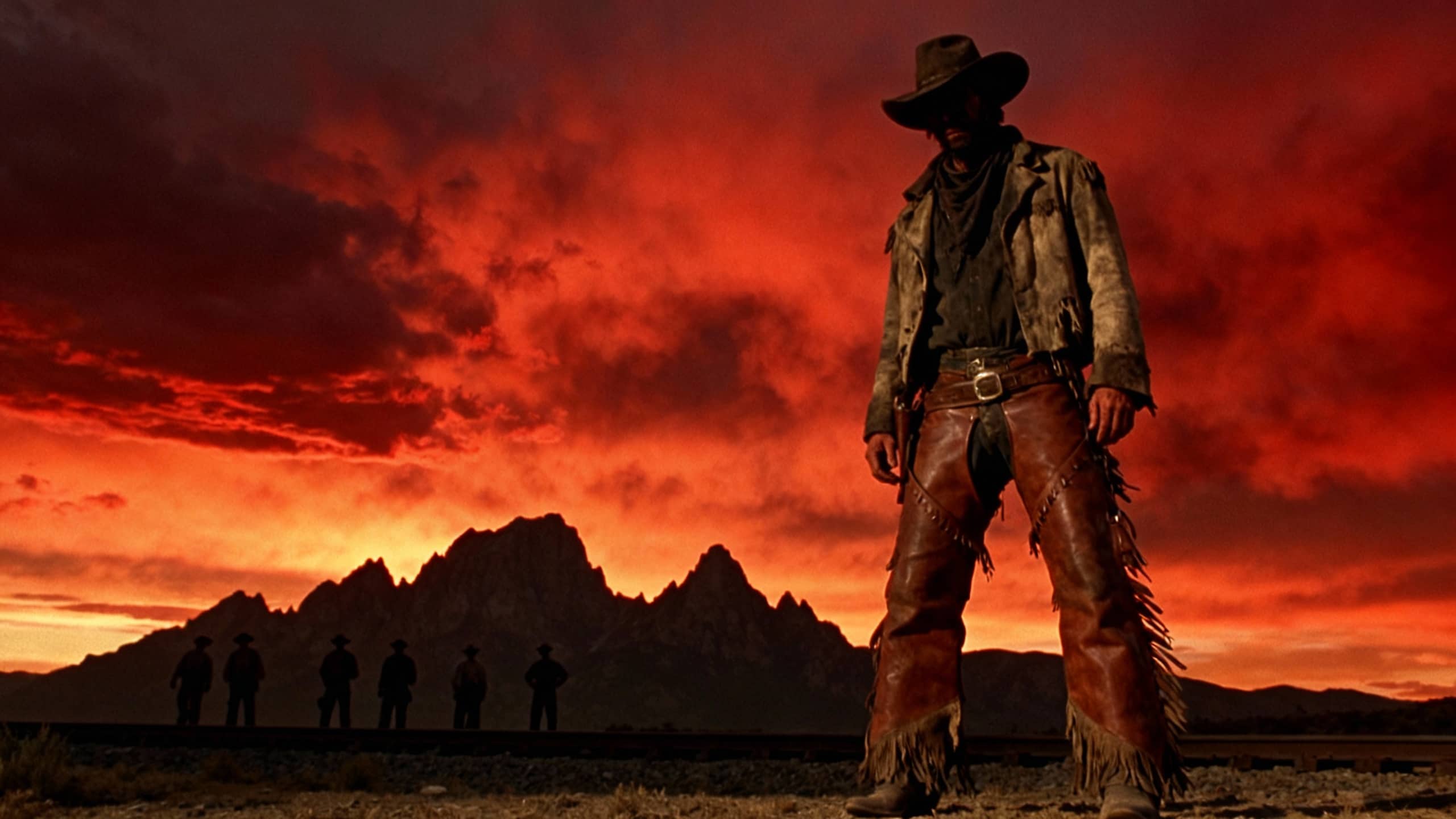 Cowboy silhouette devant coucher de soleil rougeoyant.