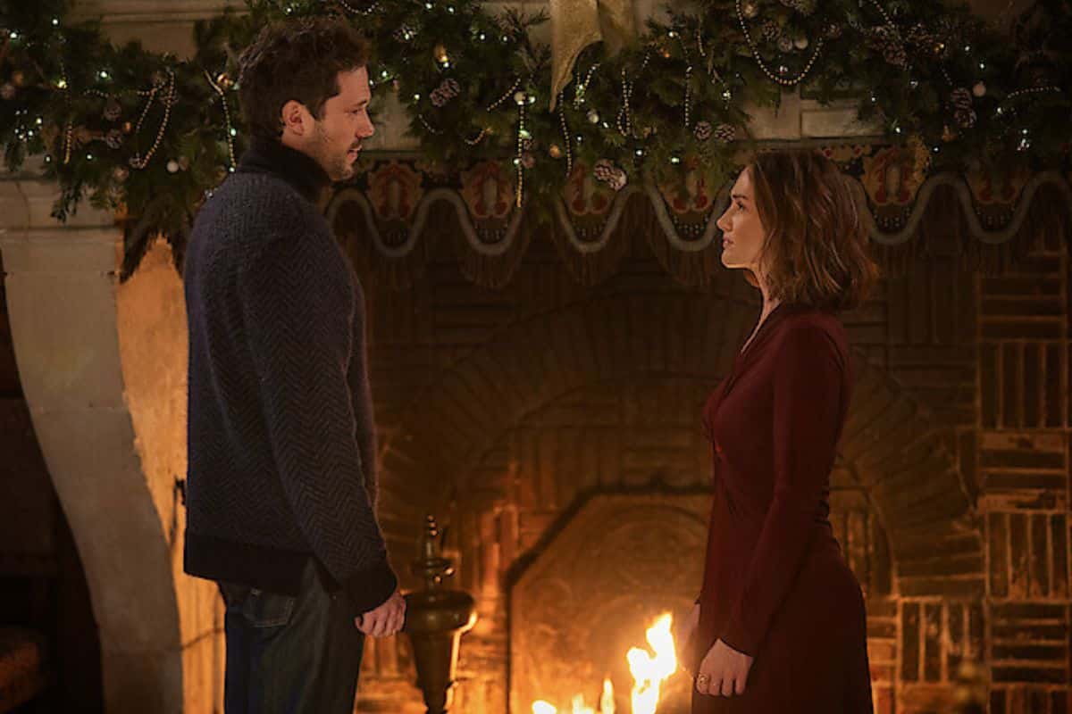 Un couple devant une cheminée décorée pour Noël.