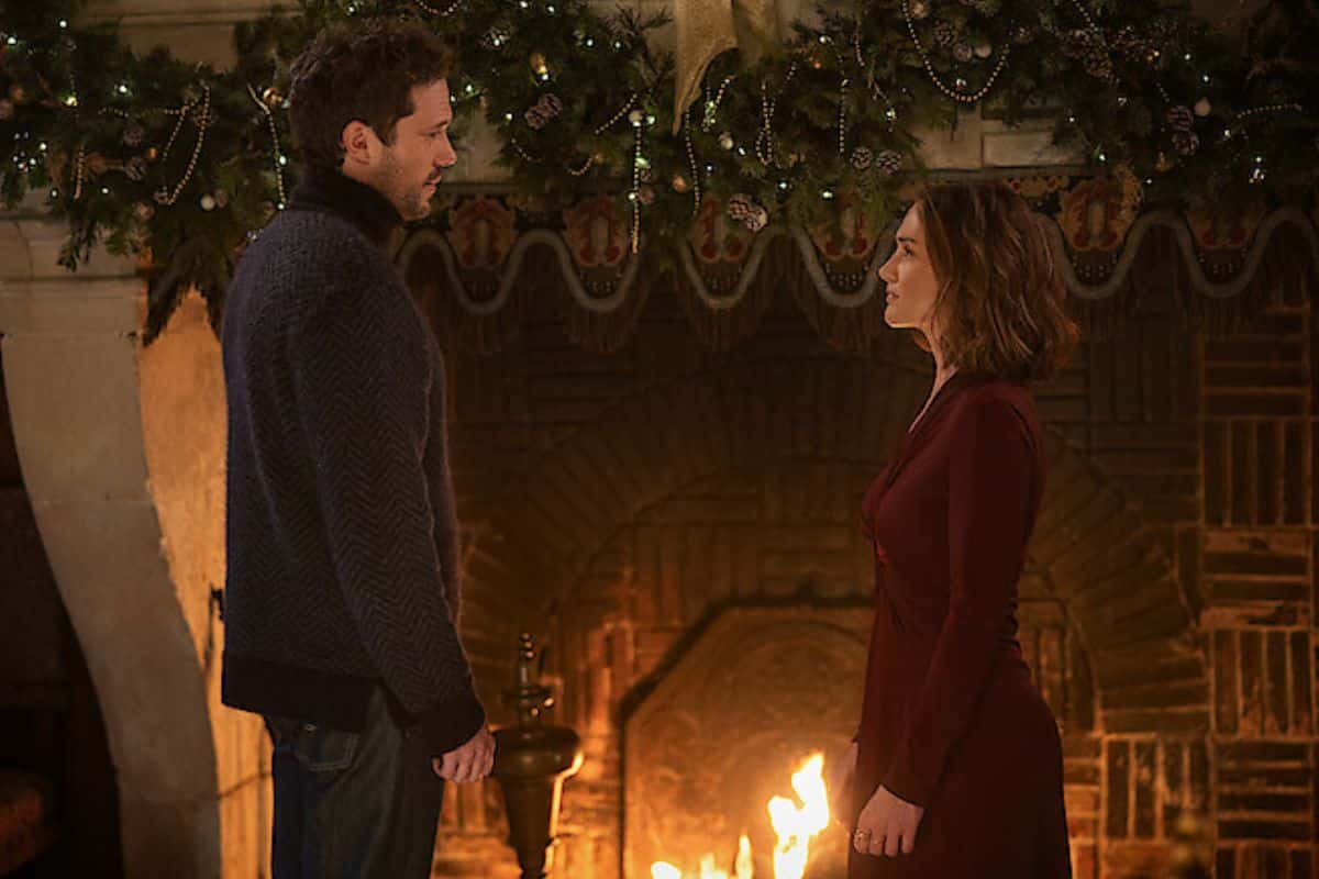 Deux personnes debout devant une cheminée décorée.