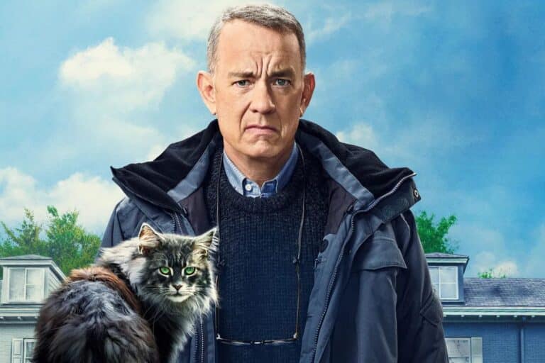 Homme sérieux avec un chat devant une maison.