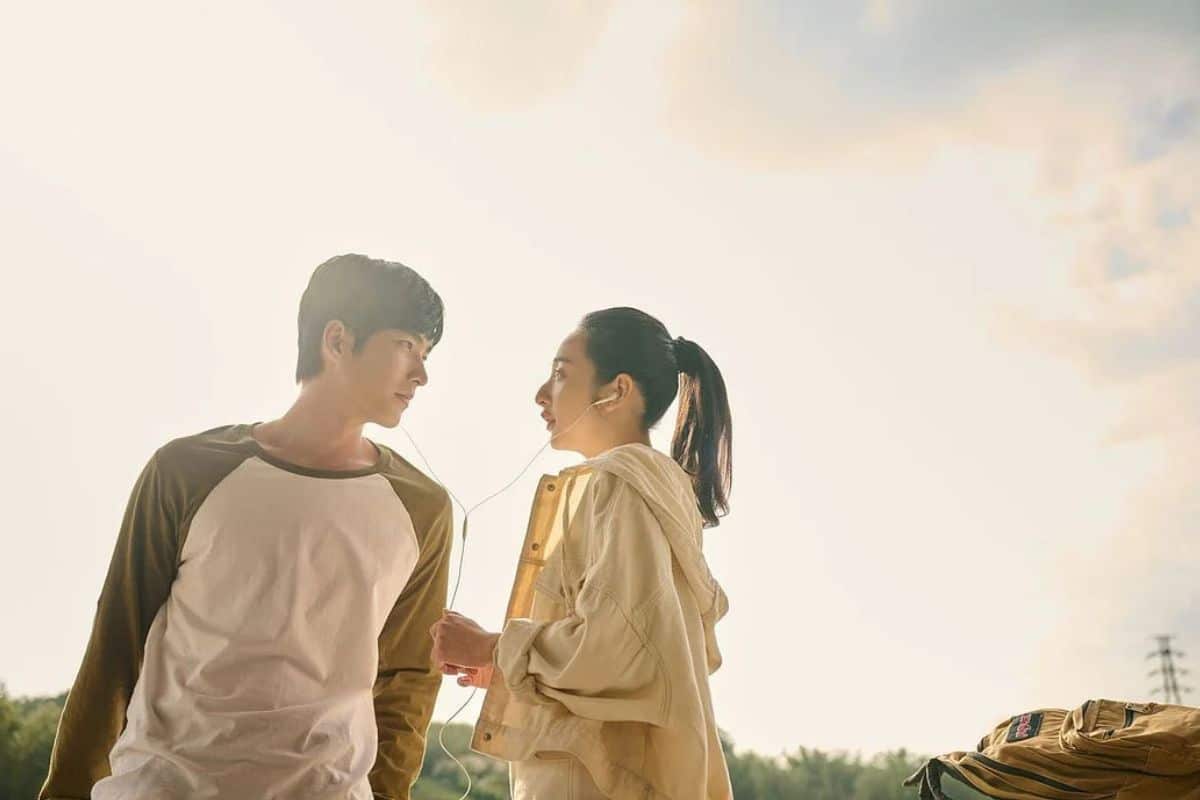 Deux personnes partageant des écouteurs au coucher du soleil.