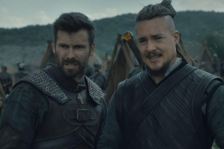 Deux hommes en armure discutent sur un champ de bataille.