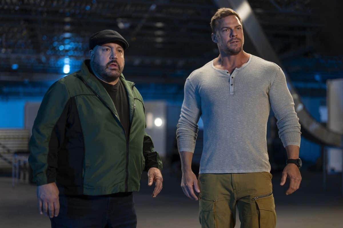 Deux hommes debout dans un hangar sombre.