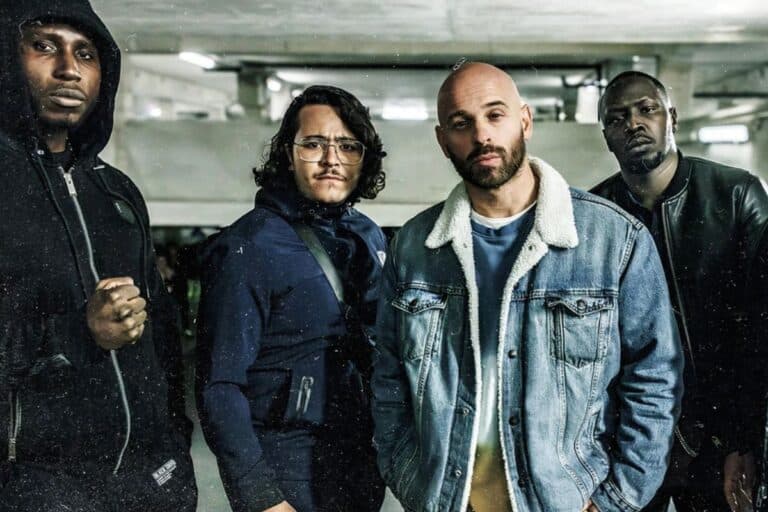 Quatre hommes debout dans un parking souterrain.