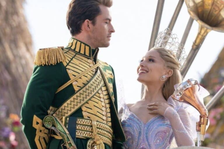 Couple en costumes royaux sourit, fête en arrière-plan.