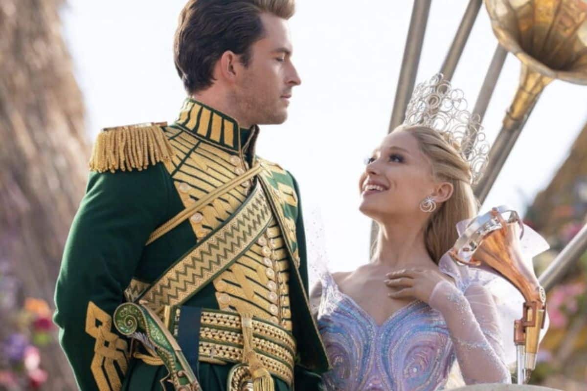 Couple en costumes royaux sourit, fête en arrière-plan.