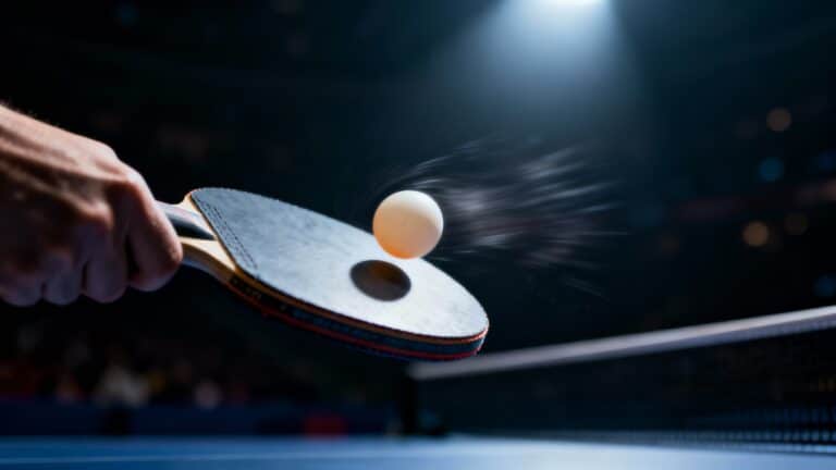 Raquette de ping-pong frappant une balle blanche.