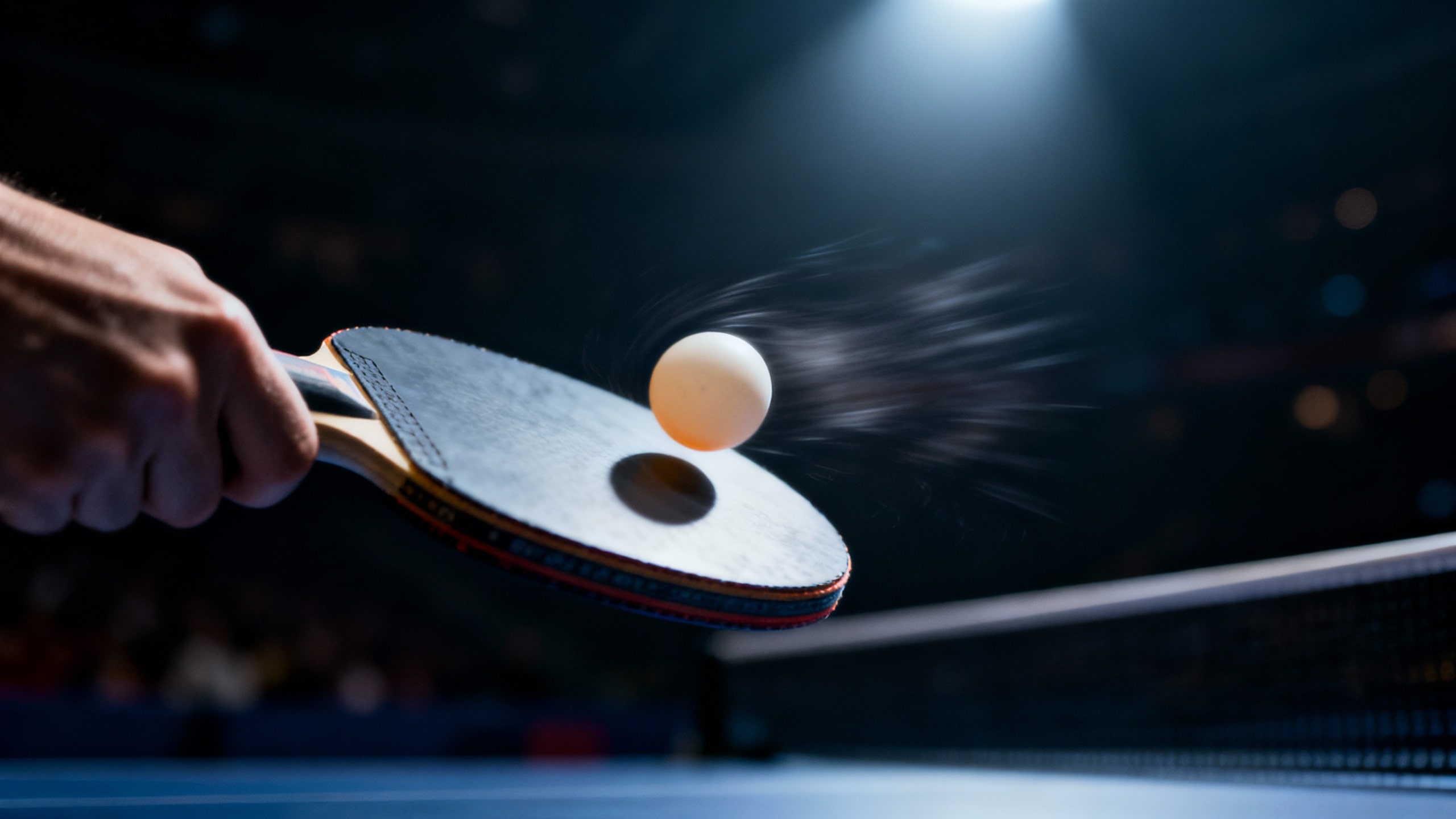 Raquette de ping-pong frappant une balle blanche.