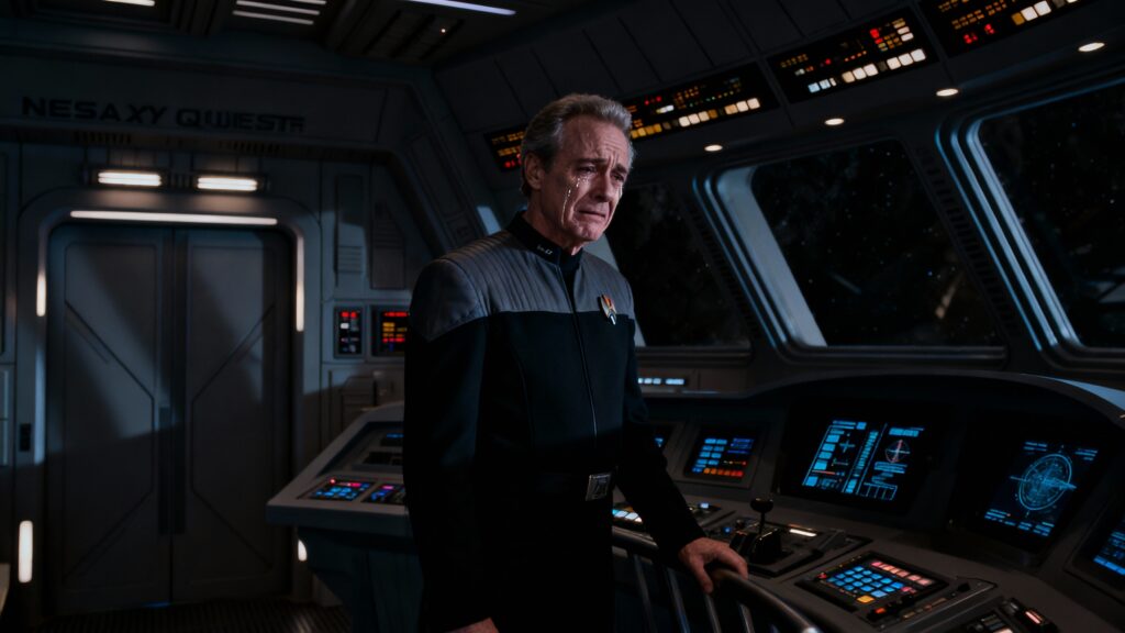 Homme en uniforme dans un cockpit futuriste, triste.