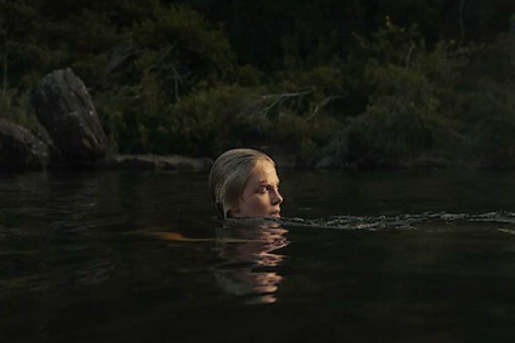 Femme nageant dans un lac, entourée de nature.