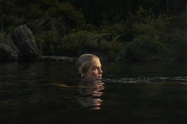 Femme nageant dans un lac, entourée de nature.