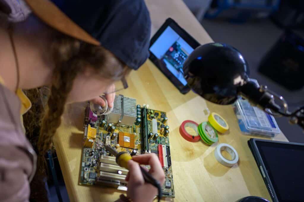 Personne réparant une carte mère avec un fer à souder.