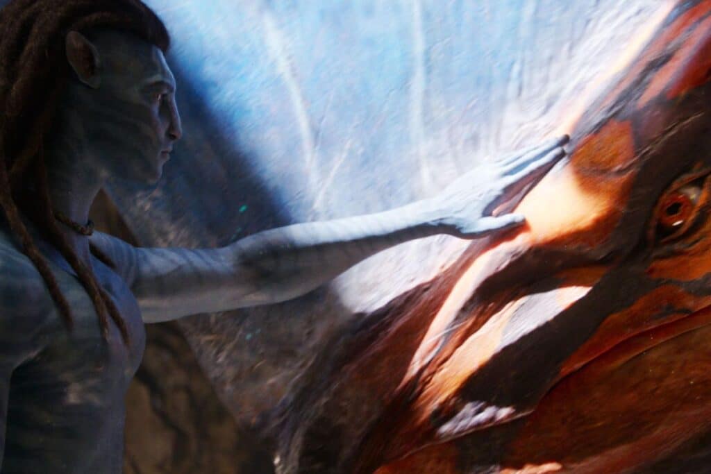 Personnage bleu touche une créature exotique colorée.