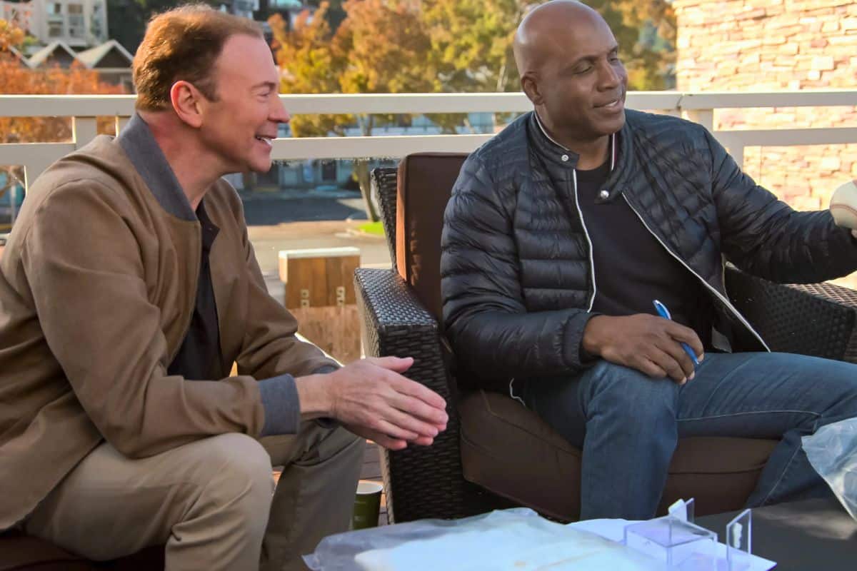 Deux hommes discutant en terrasse, l'un tient balle.