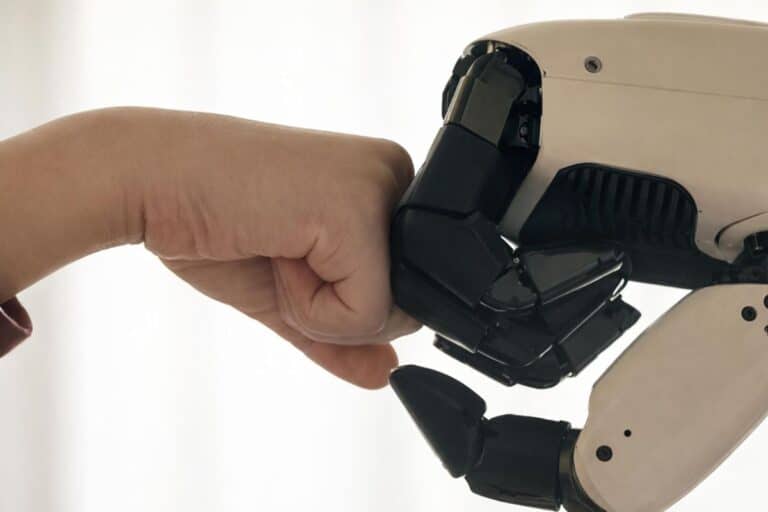 Poing humain touchant poing robotique.