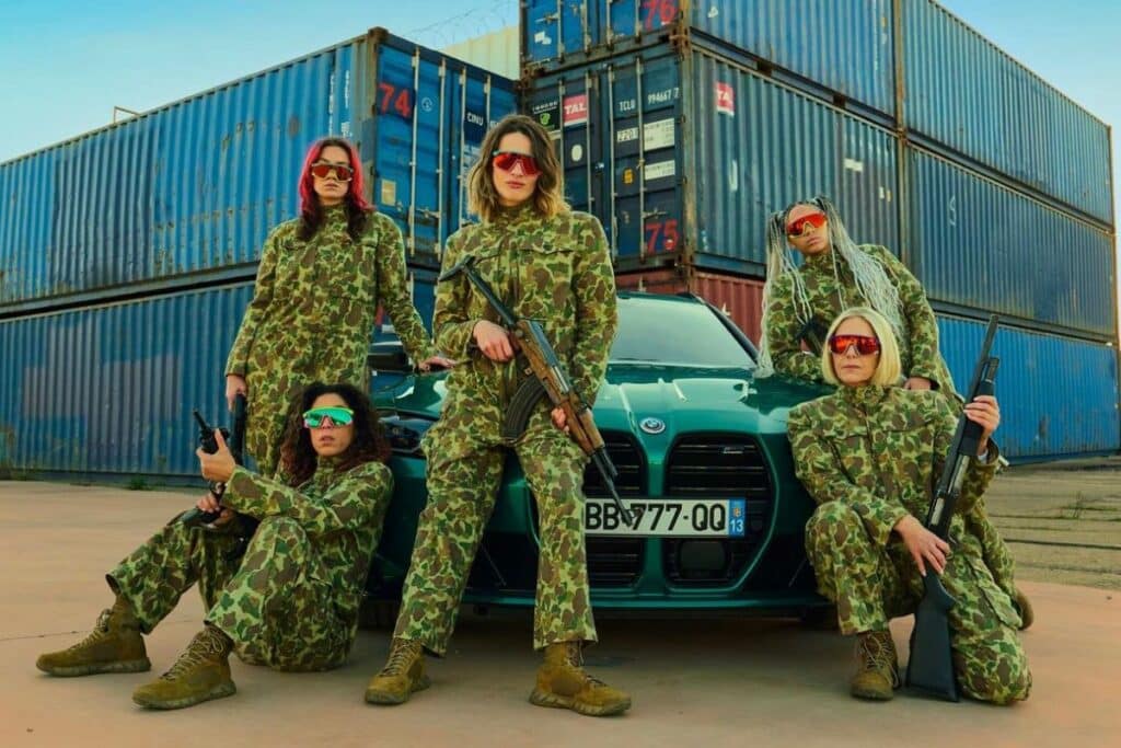 Cinq personnes en tenue camouflage devant des conteneurs.