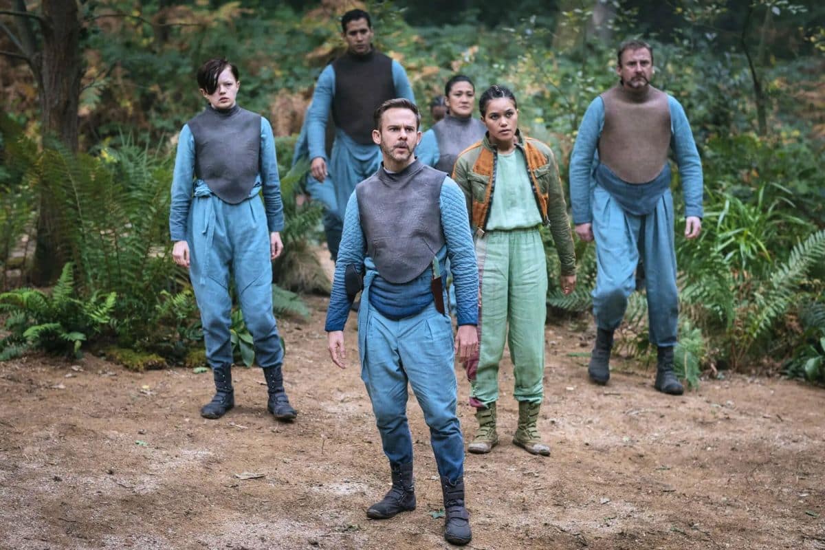 Groupe de personnes en tenues futuristes dans la forêt.