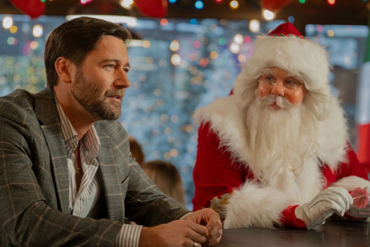 Homme discutant avec le Père Noël, lumières festives.