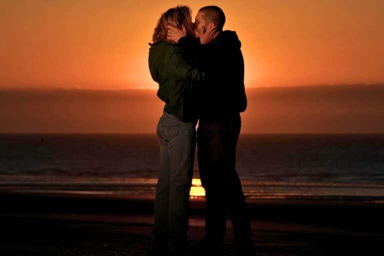 Couple s'embrassant au coucher de soleil sur la plage.
