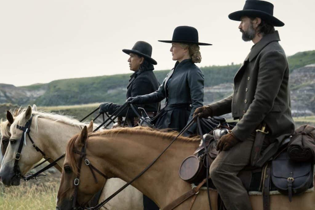 Trois cavaliers portant des chapeaux en plein air.