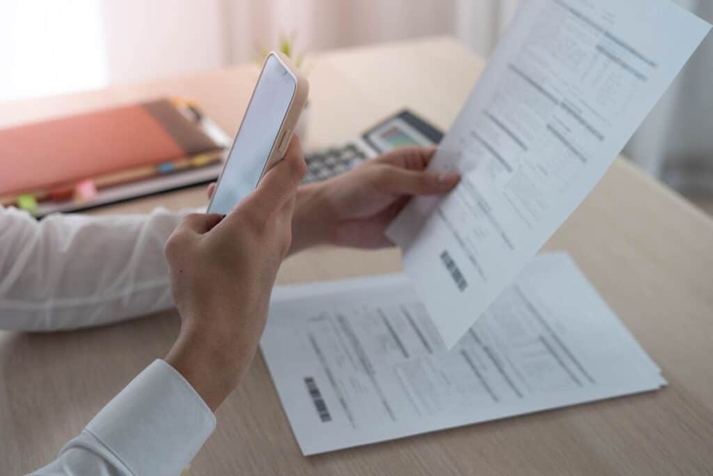 Personne scanne document papier avec smartphone.