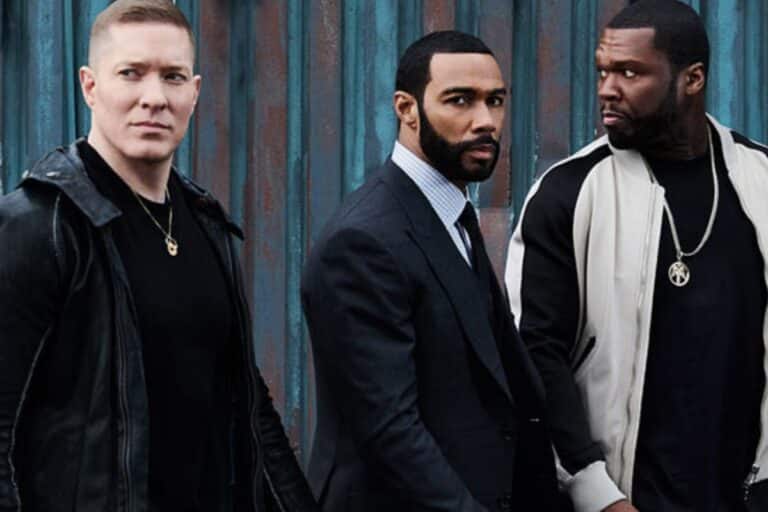 Trois hommes debout devant un mur bleu.