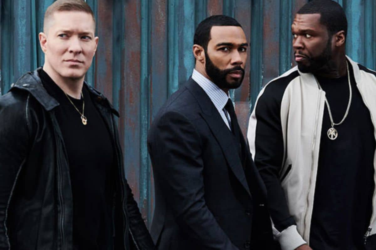 Trois hommes debout devant un mur bleu.