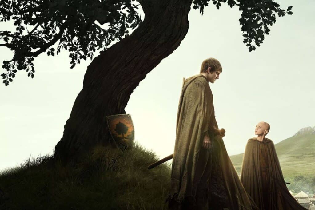 Deux personnes en capes près d'un arbre.