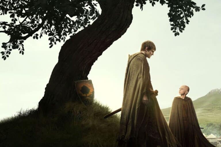 Deux personnes en capes près d'un arbre.