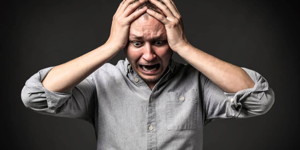 Homme exprimant stress avec les mains sur la tête.