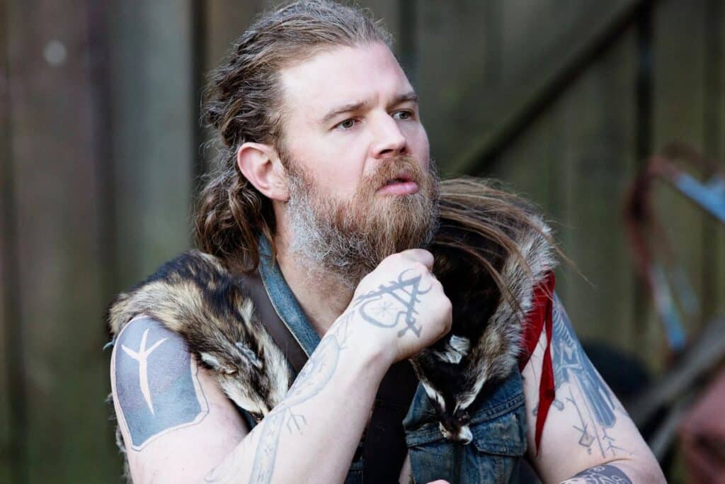 Homme barbu tatoué en tenue viking réfléchissant.